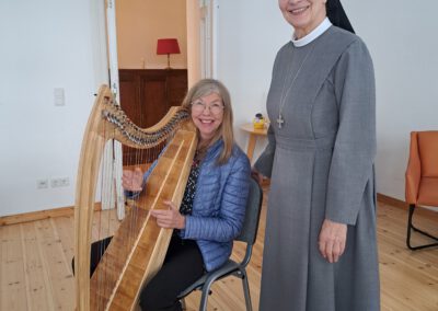 Dozentin Silke Dimitriw sitzt an Harfe von Klientin Schwester Theresita Maria von SMMP