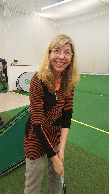 Frau mit Golfschläger im Profil steht in Golfhalle