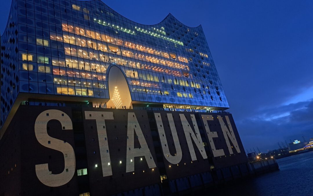 die Elbphilharmonie in Hamburg wird beleuchtet mit dem Schild Staunen