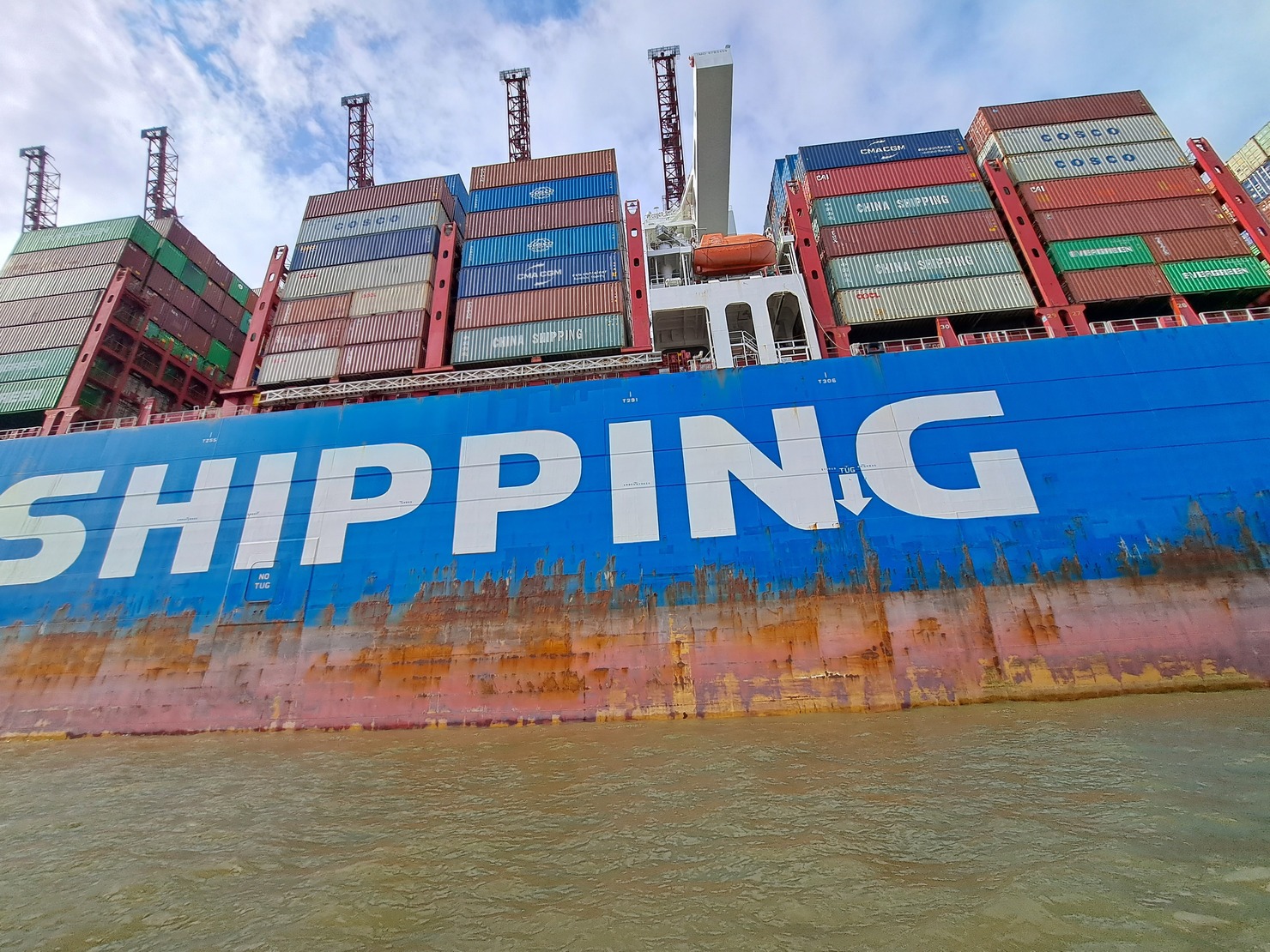 eins der größten Frachtschiffe im Hafen von Hamburg mit der Aufschrift shipping