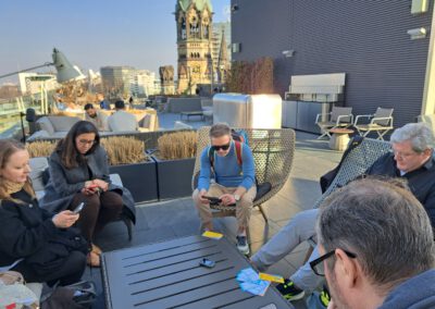 5 Personen sitzen auf Dachterrasse am Tisch im Hintergrund sieht man die Gedächtniskirche