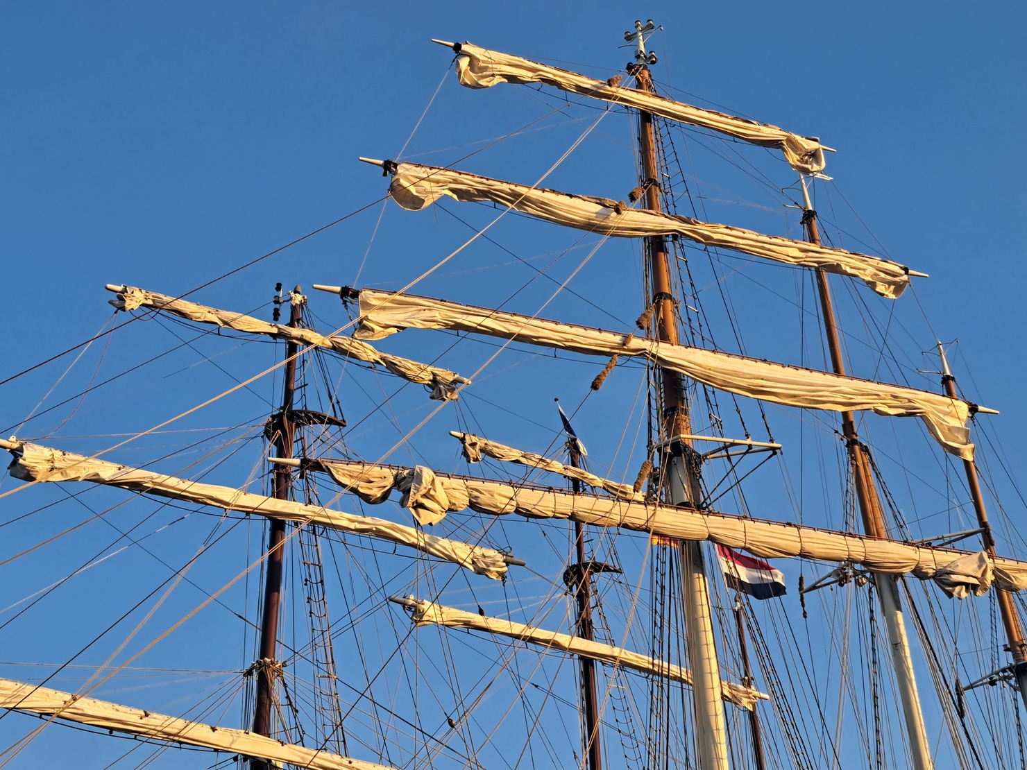 altes Segelboot liegt im Hafen -weiße Segel sind aufgerollt - gegen blauen Himmel Kieler Woche 2024 